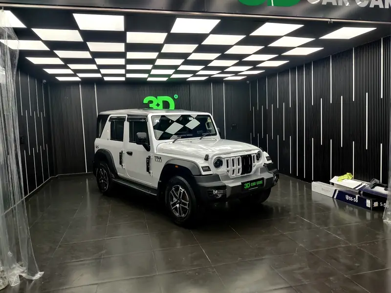 A car in the studio bay with the ceiling light array reflected along its bodywork