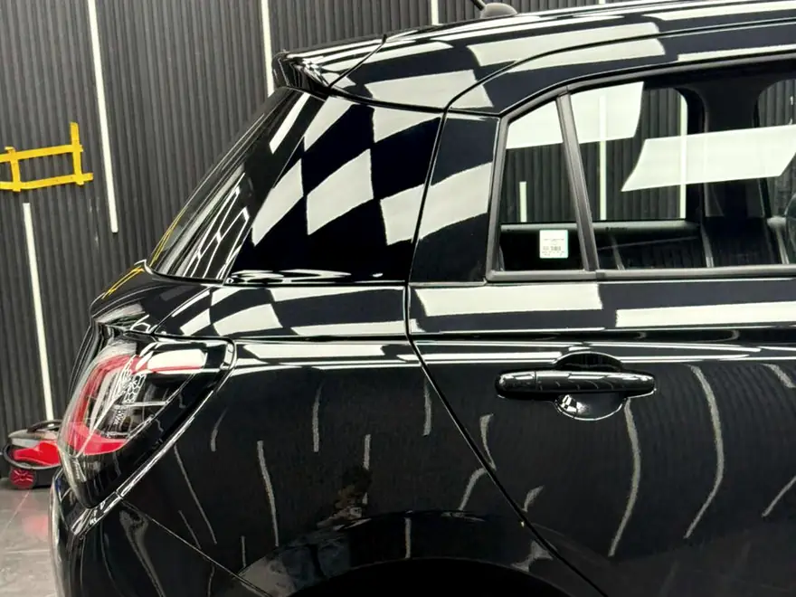 Checkerboard reflection wrapping around the rear flank of a dark hatchback