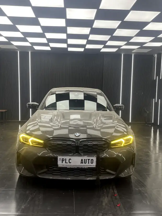 A saloon parked under the checkerboard ceiling with its headlights on