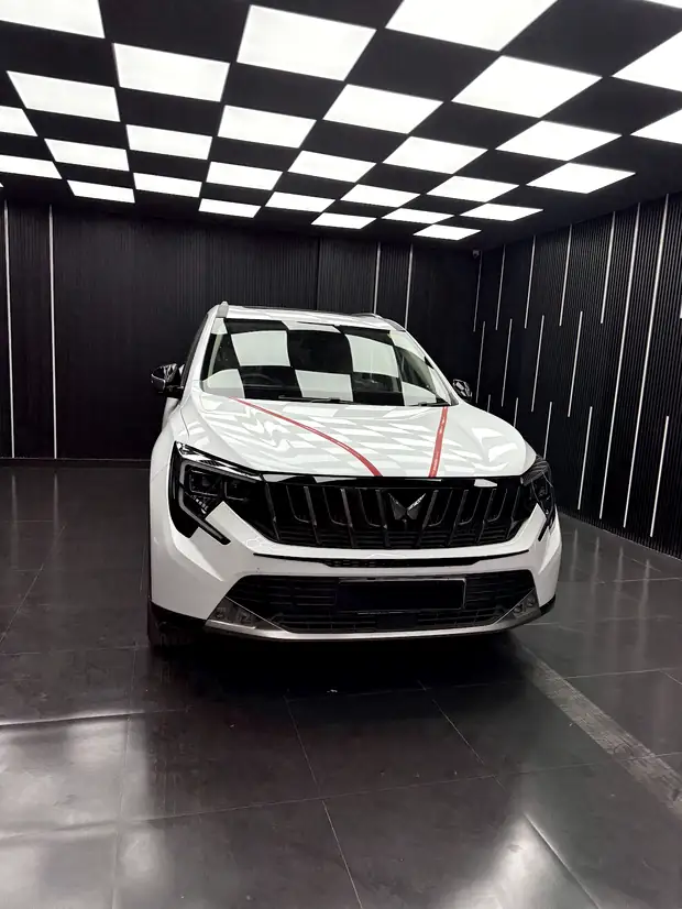 A white SUV masked with tape lines, standing under the light array